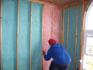 Worker installing hybrid insulation system in walls.