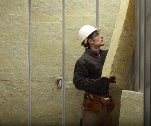 Man installing mineral wool insulation.