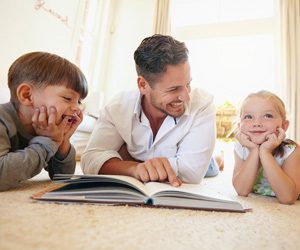 Dad reading a book to his son and daughter