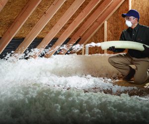 worker spraying insulation foam in an attic