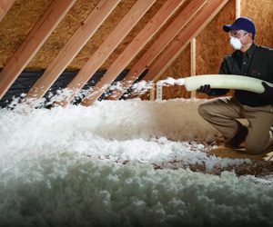 worker spraying insulation foam in an attic