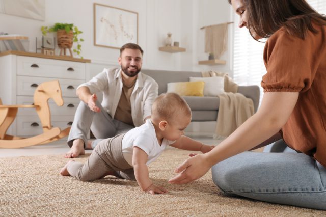 Parents sit on the floor in a nursery with their baby