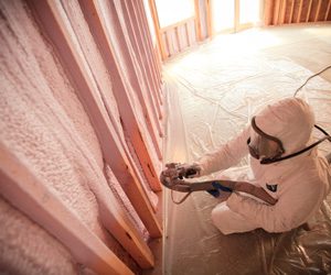 worker spraying insulation foam on a wall