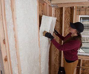 woman installing fiber glass insulation