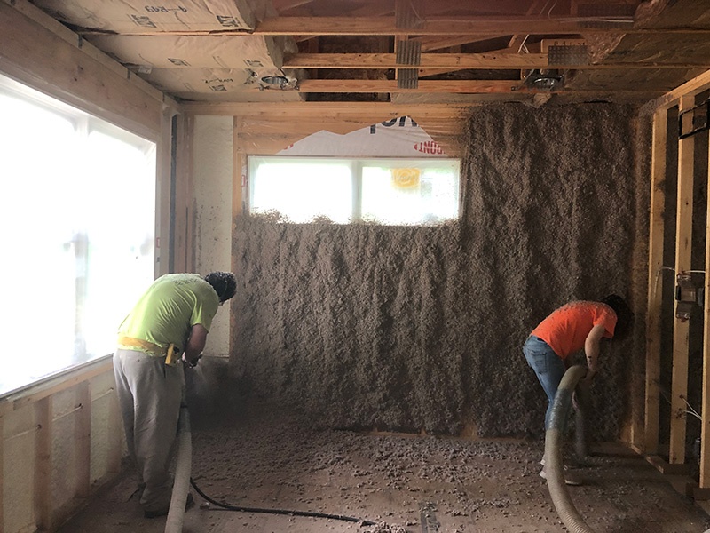 Two workers installing wet cellulose insulation