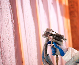 worker spraying foam insulation on a wall