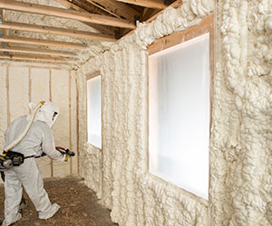 Worker in coveralls spraying foam insulation
