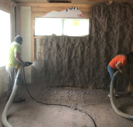 Two workers installing cellulose insulation.