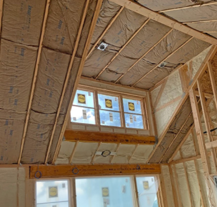 Fiberglass batts installed in a vaulted ceiling with windows.
