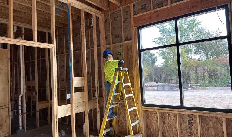 Female insulation installer, completing a batt insulation install at a wedding venue