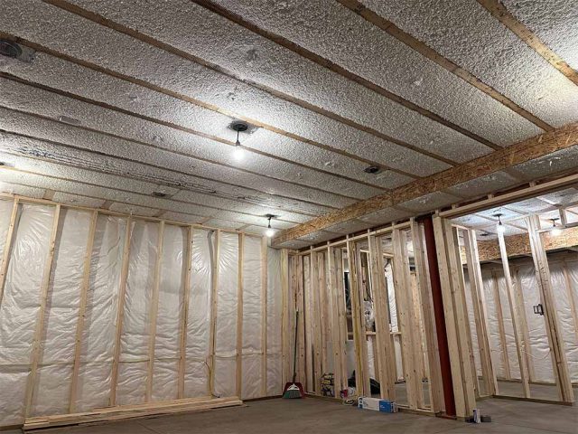 Basement ceiling with netting installed and blow-in insulation filled between joists.