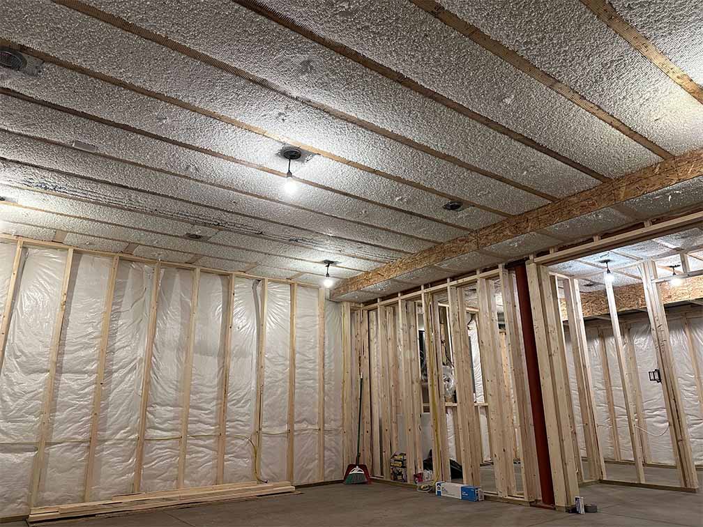 Basement ceiling with netting installed and blow-in insulation filled between joists.