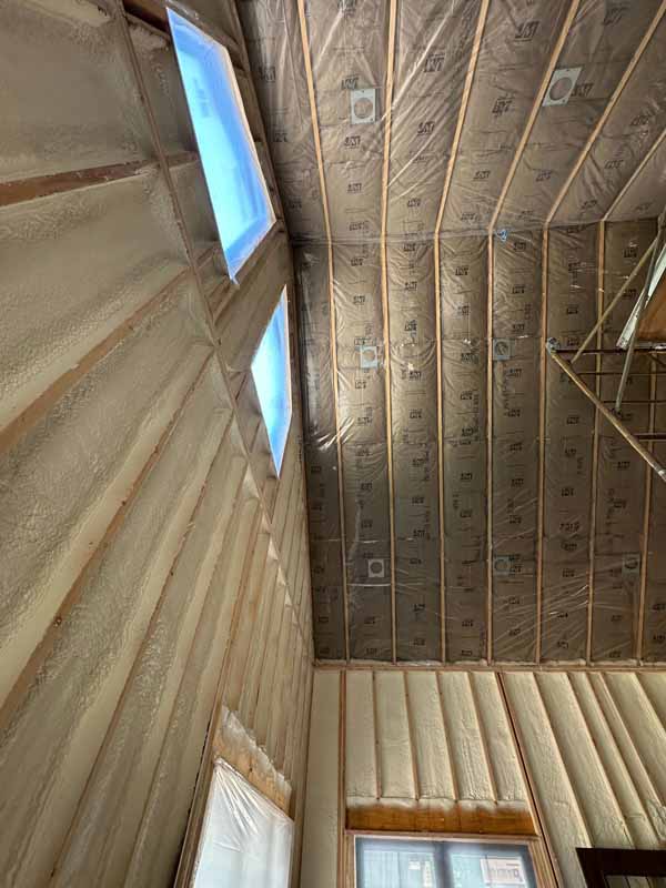 R-49 fiberglass batts neatly installed between cathedral-ceiling rafters in a new Wolf Lake home, Baldwin MI.