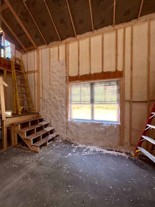 Exterior wall mid-way through hybrid process—closed-cell foam base with white Spider fiberglass being blown in.