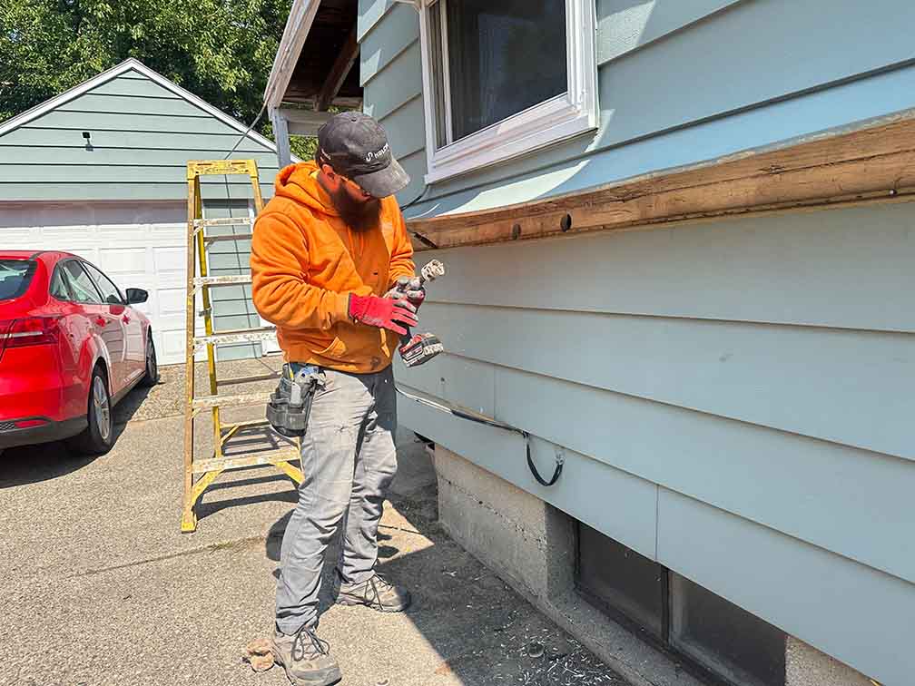 Technician preparing the exterior wall for blown-in cellulose insulation.