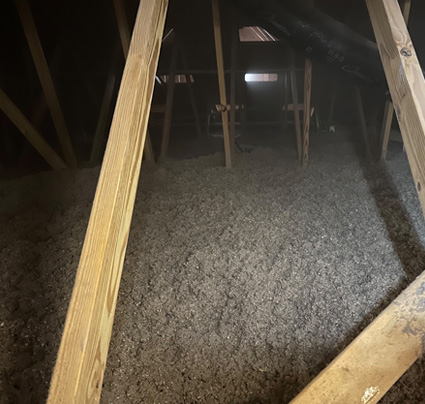 Whitson Insulation blown-in cellulose insulation spread evenly across an attic floor between diagonal wood braces, with a gable vent in the background in Grand Rapids, Michigan.